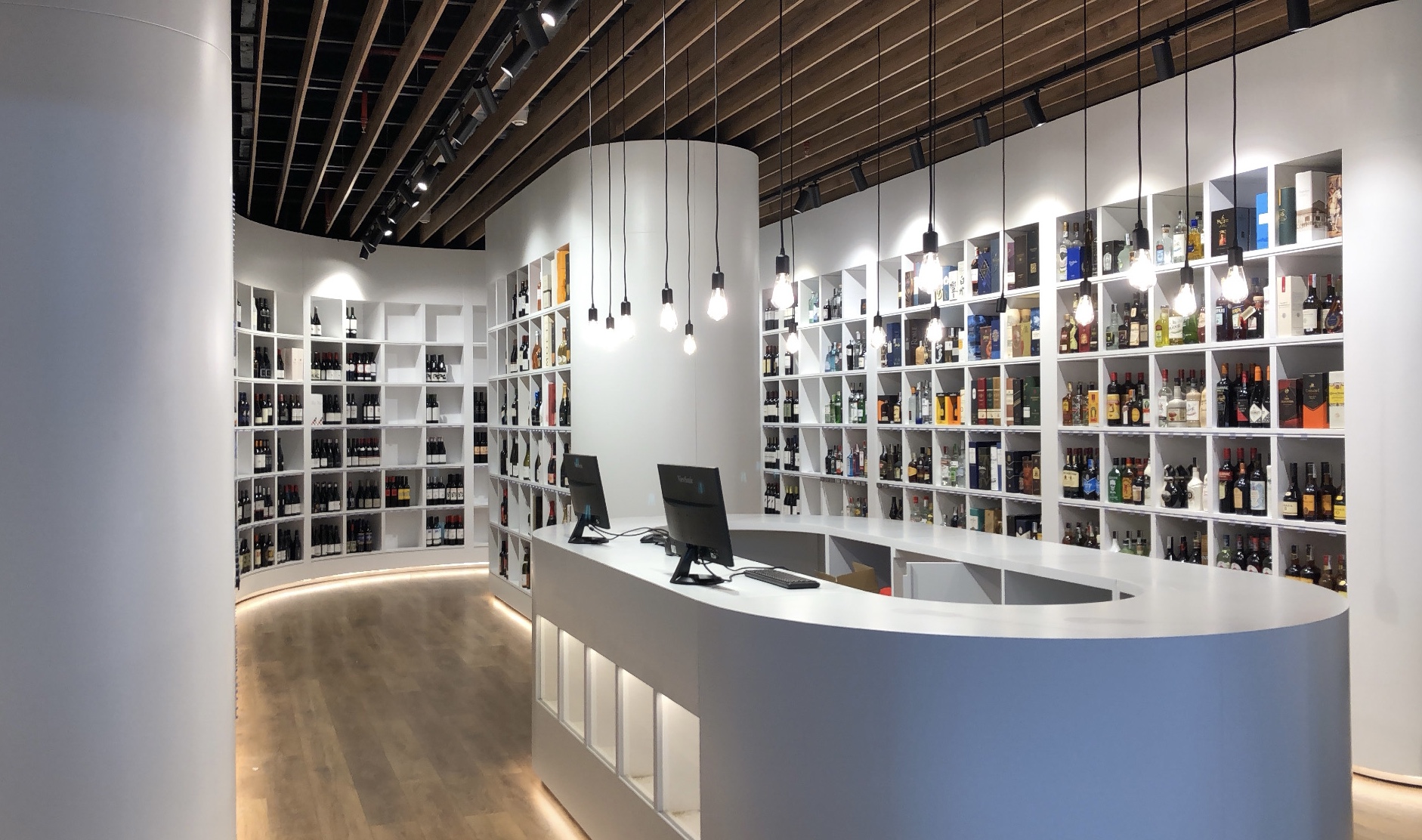 Counter area with a white curved column, shelving and a slatted timber ceiling over exposed services