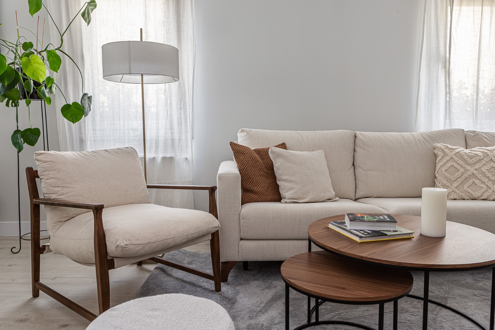 Living room with beige sofa, wooden armchair and round coffee tables