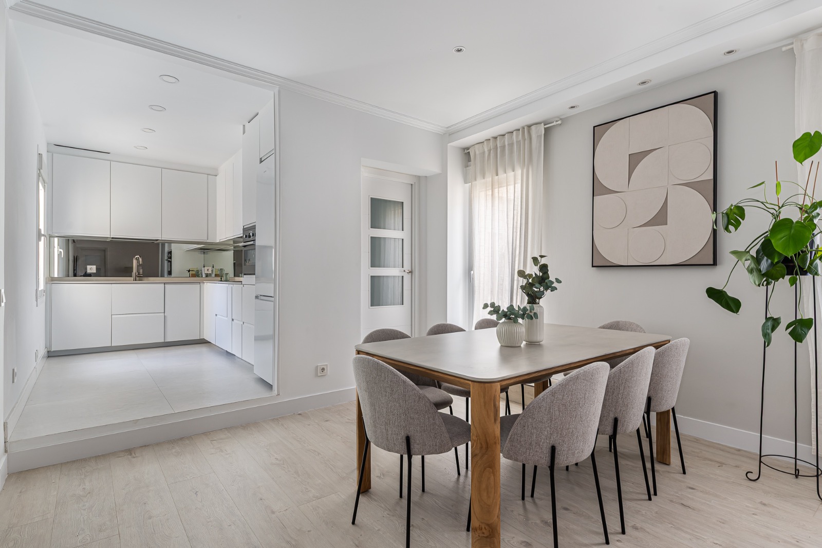 Open-plan kitchen and dining area with a wooden table and grey upholstered chairs — Fernán González Residence