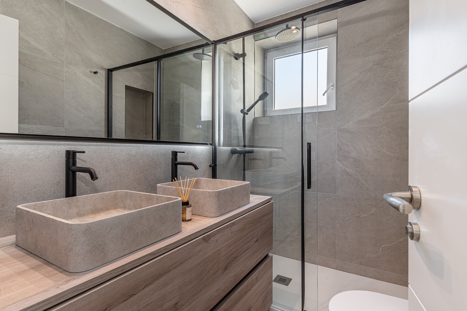 Bathroom with double stone basins, black fixtures and glass shower screen