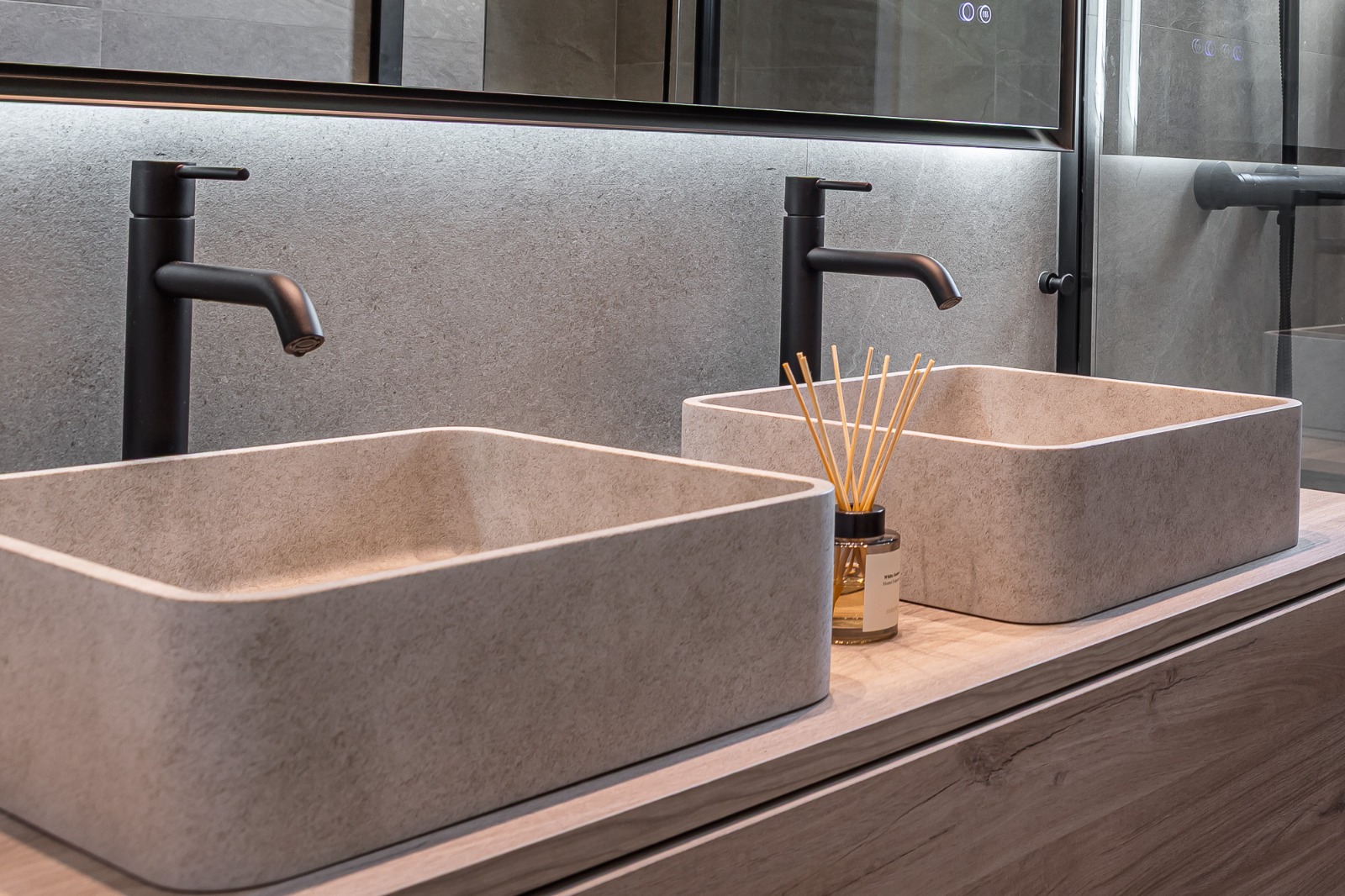 Detail of double stone basins with black fixtures on a wood-effect vanity