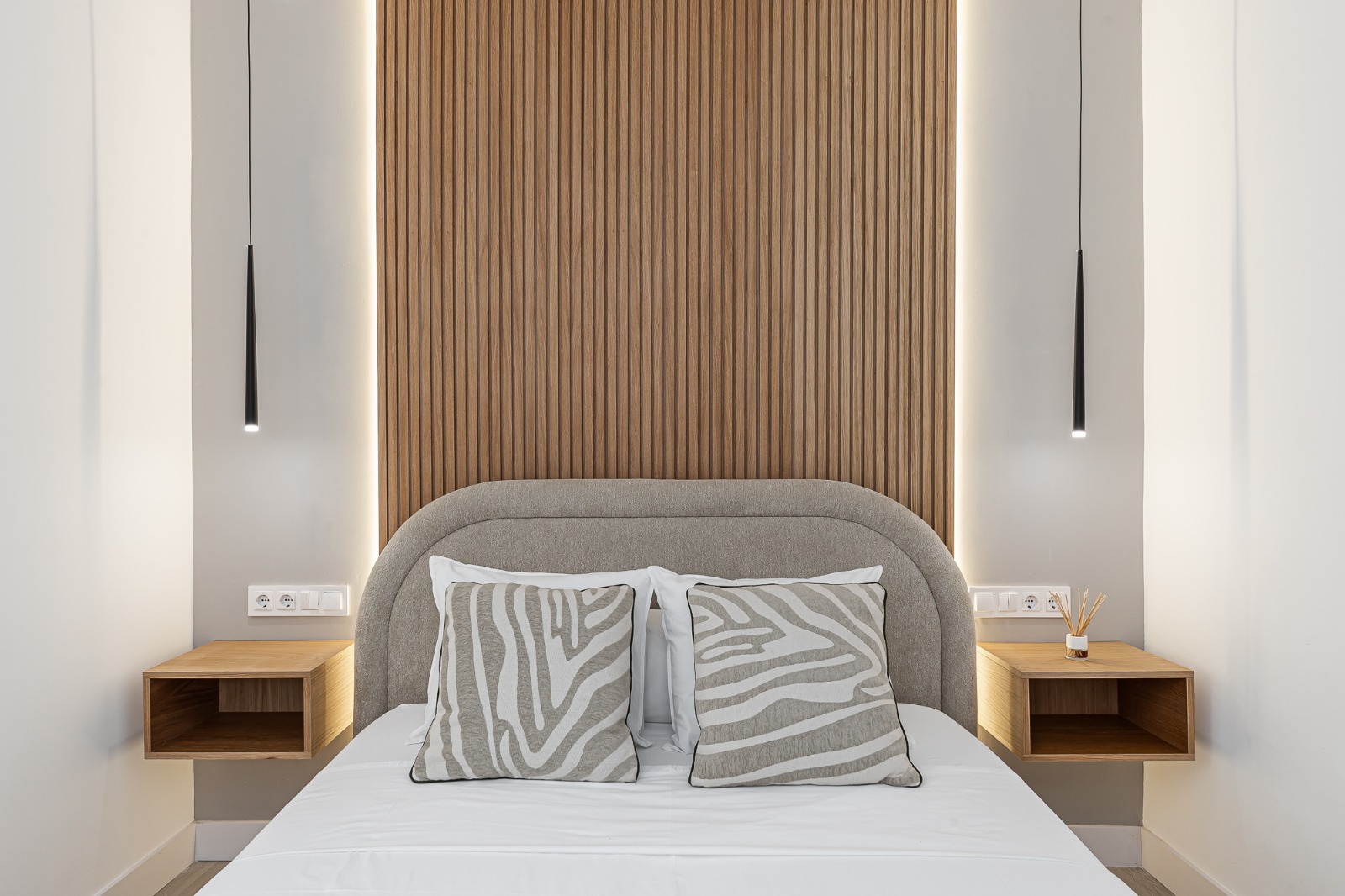 Bedroom with slatted wood headboard, upholstered bed and pendant lamps