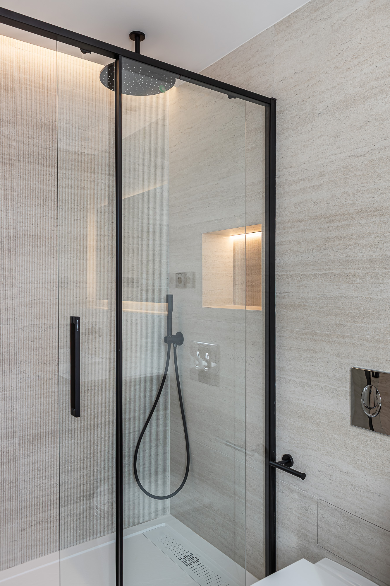 Walk-in shower with a black-framed glass screen, rain shower head and lit wall niche